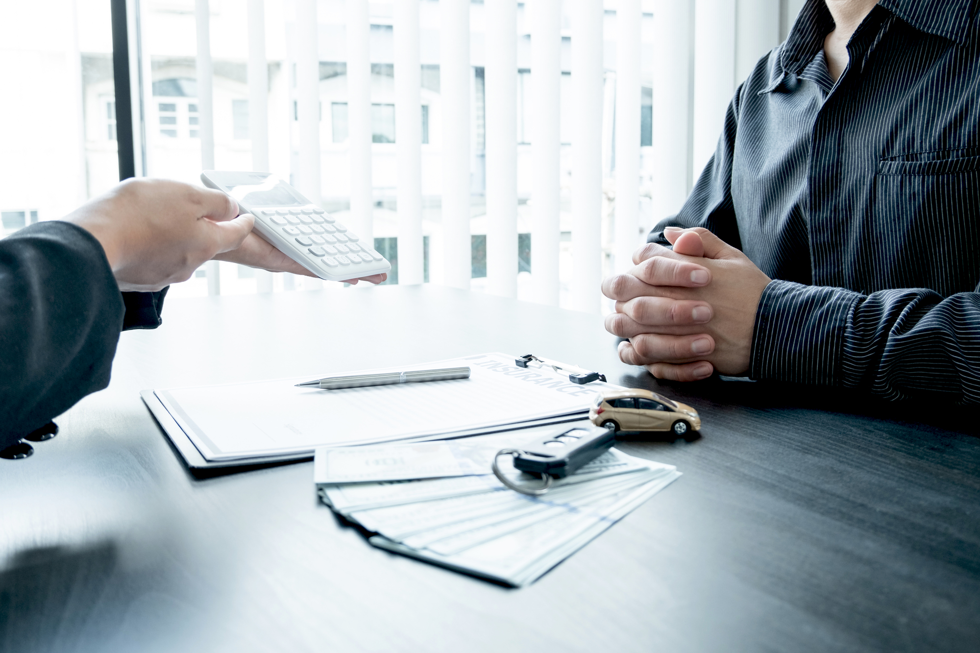 The car dealer advises the customer about insurance details and car rental information Ready delivers the keys after signing the rental contract.